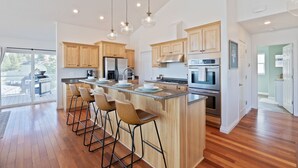 A modern kitchen with wooden cabinets, stainless steel appliances, and a central island with bar stools.