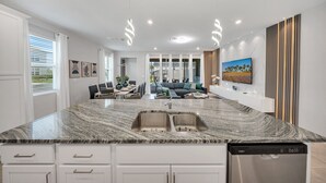 Eine moderne Küche mit Granit Arbeitsplatte, Edelstahlspüle und einem integrierten Geschirrspüler.