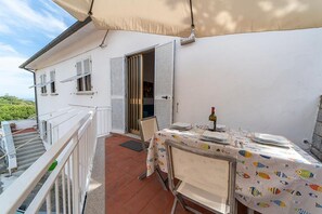 A balcony with a table set for dining, a chair, and a bottle of wine.