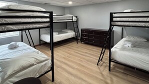 A dormitory room with bunk beds, a desk, and a dresser.