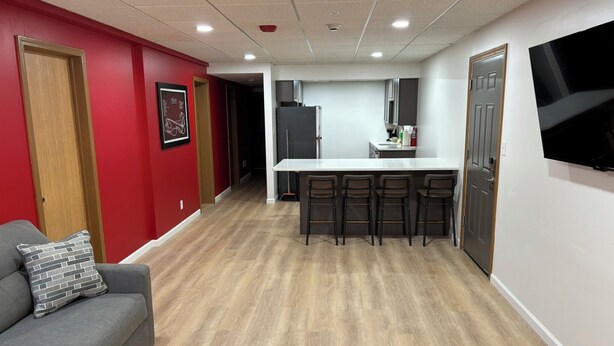 A modern kitchen with a white countertop and four bar stools.