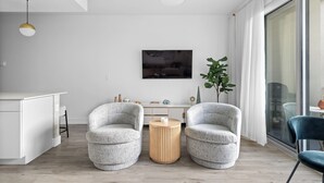 A modern living room with two grey armchairs, a round wooden side table, a white console table, and a large window with a view. - Sarasota Poolside Stylish Retreat w/Grill, Fishing (Sarasota)
