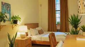 Et pænt opredt soveværelse med seng, sengeborde, lampe og potteplanter.