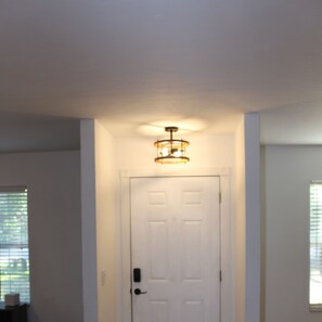Enter a serene hallway leading to a room with a door featuring a circular light fixture above.