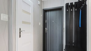 A modern hallway with a grey door, a white door with horizontal panels, and a black coat rack with a blue item hanging.