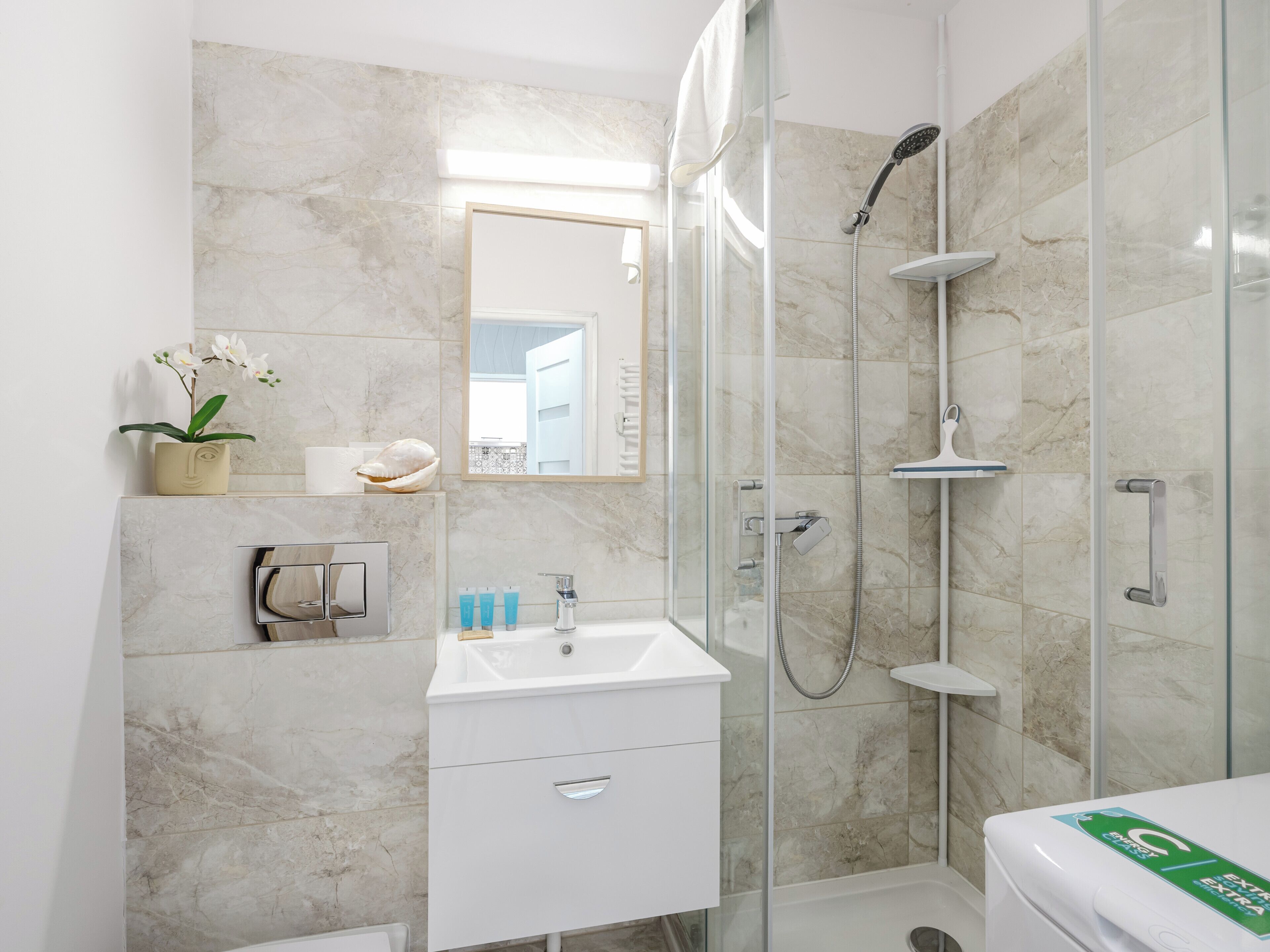 Une salle de bain moderne avec une douche à parois de verre, un lavabo blanc et un miroir.