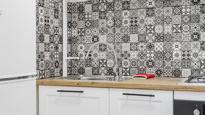 A kitchen with white cabinets, a wooden countertop, and a backsplash with black and white tiles.