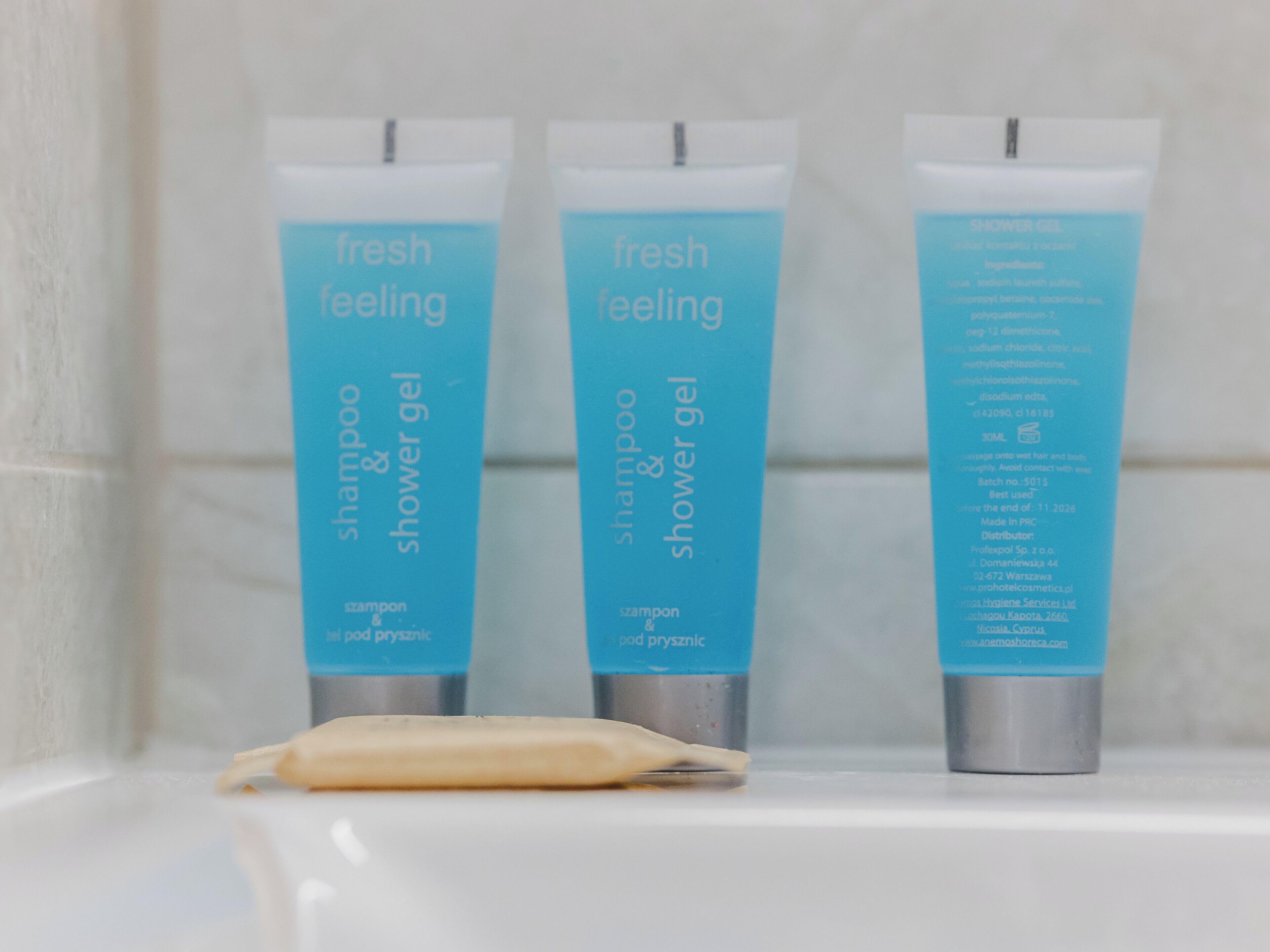 Drei Flaschen 'fresh feeling' Shampoo und Duschgel auf einem Badezimmerschrank.