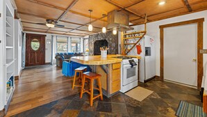 Une cuisine dotée d’un îlot central, de tabourets en bois, d’une cuisinière et d’un mur en pierre.