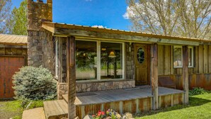 Un chalet rustique avec une cheminée en pierre, de grandes fenêtres et une terrasse en bois.