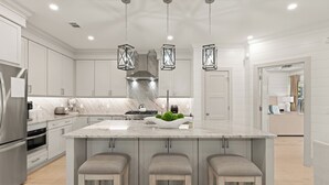 A modern kitchen with marble countertops, stainless steel appliances, and pendant lighting. - Enchanted Getaway: Coastal Escape | Private Pool | Easy Walk to Beach + Village (Saint Simons Island)