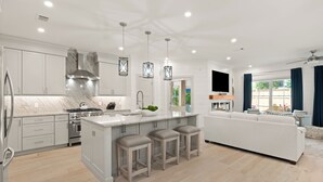 A modern kitchen with white cabinetry, a large island with stools, stainless steel appliances, and pendant lighting. - Enchanted Getaway: Coastal Escape | Private Pool | Easy Walk to Beach + Village (Saint Simons Island)