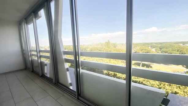 Un balcón con ventanas amplias que dan a un paisaje verde.