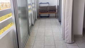 Un balcón con puerta corredera de vidrio, un banco y vista panorámica de la ciudad.