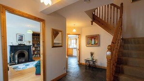 A spacious hallway with a wooden staircase, a fireplace, and a dining area with a table and chairs.