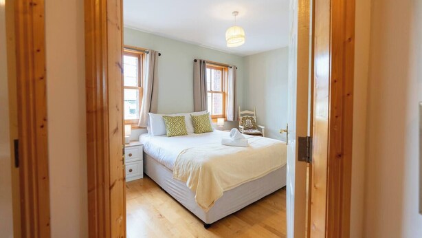A bedroom with a bed, bedside tables, a chair, and a window.