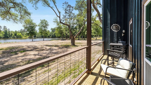 Un balcón con vistas a un lago y árboles, una mesa y una silla.