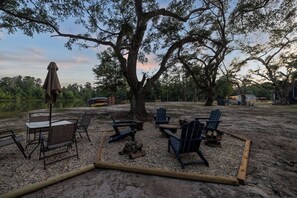 Un espacio al aire libre con mesas y sillas, rodeado de árboles y un gran árbol en el centro.