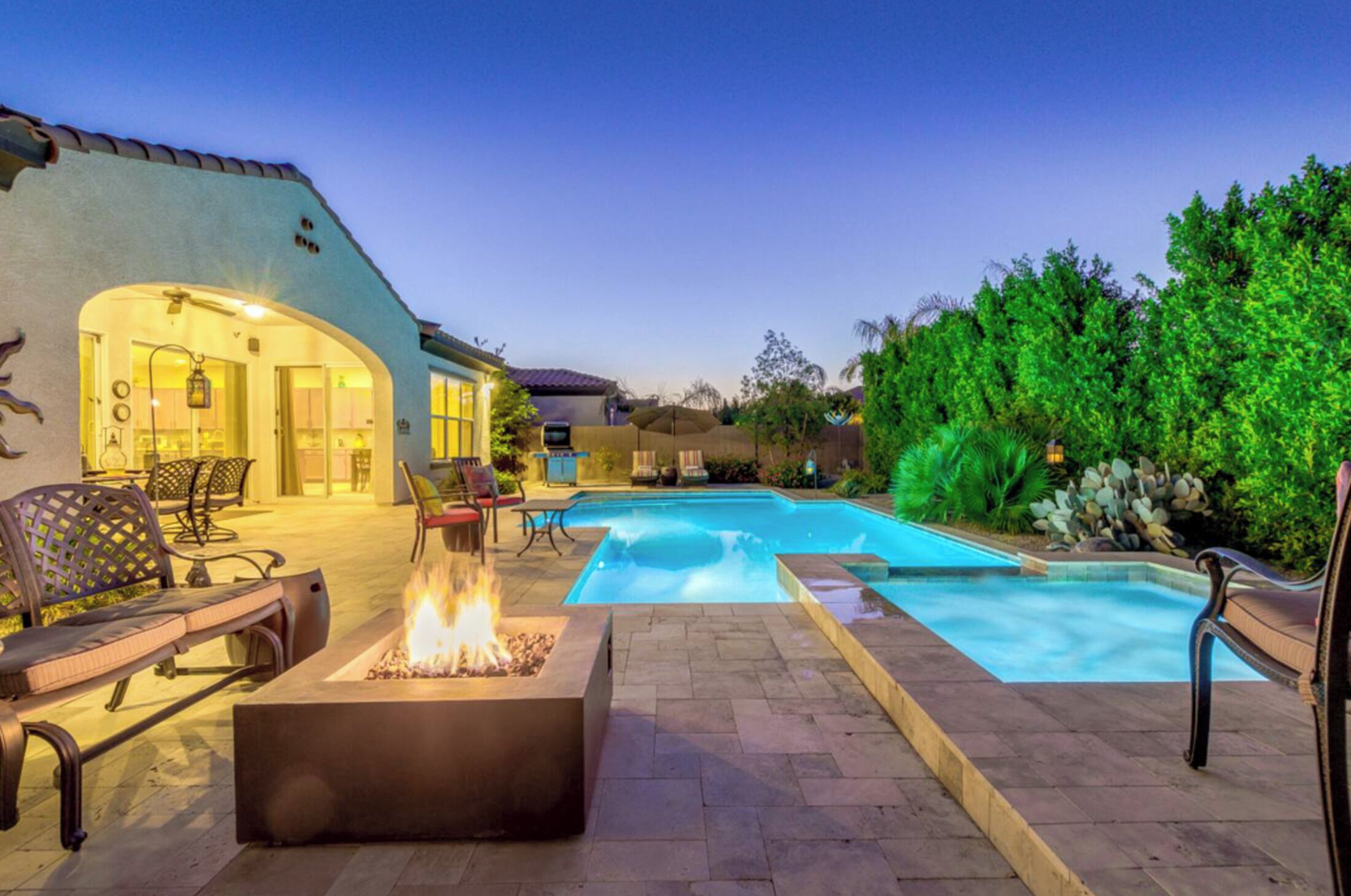 A backyard with a swimming pool, outdoor seating, and a fire pit.