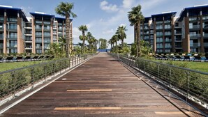 Une longue passerelle en bois, bordée de bâtiments modernes dotés de balcons, qui mène à un point de vue éloigné.
