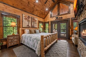 Une chambre à coucher dans un chalet en rondins, avec un lit, une tête de lit en bois et une cheminée.