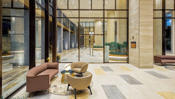 Un vestíbulo moderno con pared de vidrio, mostrador de recepción y zonas de estar.