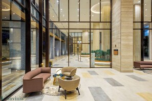 A modern lobby with a glass wall, a reception desk, and seating areas. - 2BR Luxury in District 7 (Ho Chi Minh City)