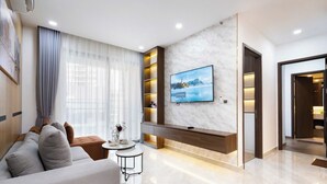 Una sala de estar moderna con un sofá, una mesa de centro, un televisor montado en una pared de mármol y un mueble de estanterías empotrado.