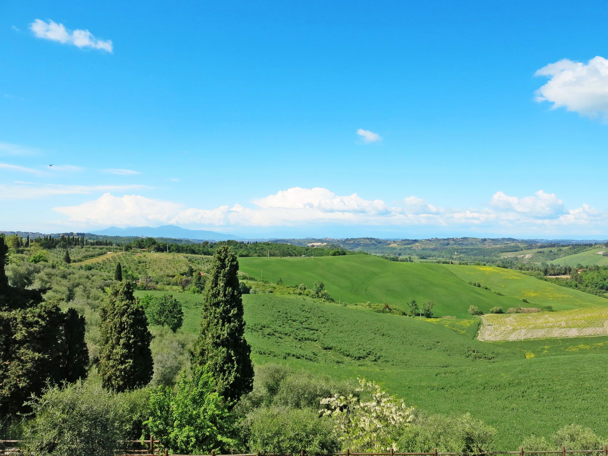 A panoramic view of a lush green landscape with rolling hills and a clear blue sky.