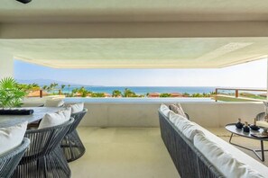 Um terraço com mobiliário de vime, piscina e vista para o mar.