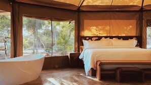 A tent-style bedroom with a large bed, a bathtub, and a view of the outdoors. - LJS Chichikan Eco Luxury Retreat  (Valladolid)