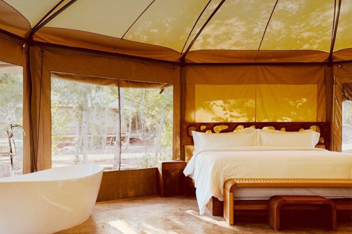 Una habitación con carpa que incluye una cama grande, una bañera y vistas al exterior.