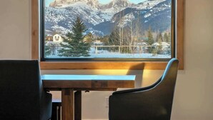 Ein Zimmer mit großem Fenster und Blick auf verschneite Berge und einen See.