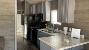 A modern kitchen with grey cabinets, stainless steel appliances, and a marble countertop.