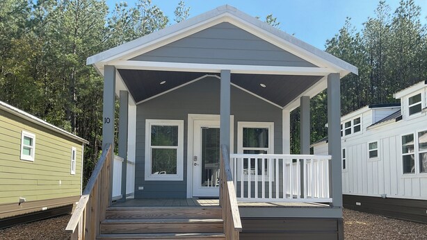 A small, single-story cabin with a porch and a set of stairs leading to the entrance.