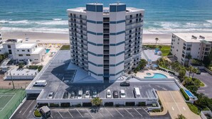 Ein Hochhaus-Hotel mit Pool, Parkplatz und Blick auf den Strand.