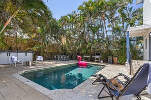 A swimming pool with a pink flamingo float, surrounded by palm trees and outdoor furniture. - Heated Pool, Outdoor Dining & Grill, Near the Beach - Heart of Punta Gorda - Roelens (Punta Gorda)
