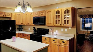 A kitchen with wooden cabinets, a black refrigerator, a microwave, and a coffee maker. - Romantic couples getaway in awesome Bluford with WiFi, Fireplace, and Game Room (Bluford)