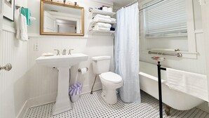 A bathroom with a pedestal sink, toilet, bathtub, and a shower curtain. - Shanty Bellum Too | 2/1, Washer/Dryer, Full Kitchen (Natchez)