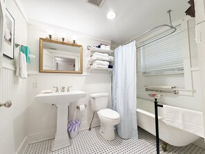 A bathroom with a pedestal sink, toilet, bathtub, and a shower curtain. - Shanty Bellum Too | 2/1, Washer/Dryer, Full Kitchen (Natchez)