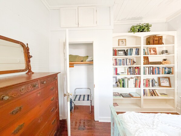 Un dormitorio con un aparador de madera, una cama, una estantería y una puerta que da a un armario.