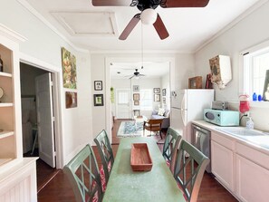 Una cocina con una mesa de comedor, sillas, un ventilador de techo y un refrigerador.