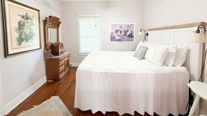 A bedroom with a bed, dresser, ceiling fan, framed picture, and a window with blinds. - Shanty Bellum Too | 2/1, Washer/Dryer, Full Kitchen (Natchez)