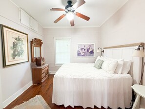 A bedroom with a bed, dresser, ceiling fan, framed picture, and a window with blinds. - Shanty Bellum Too | 2/1, Washer/Dryer, Full Kitchen (Natchez)