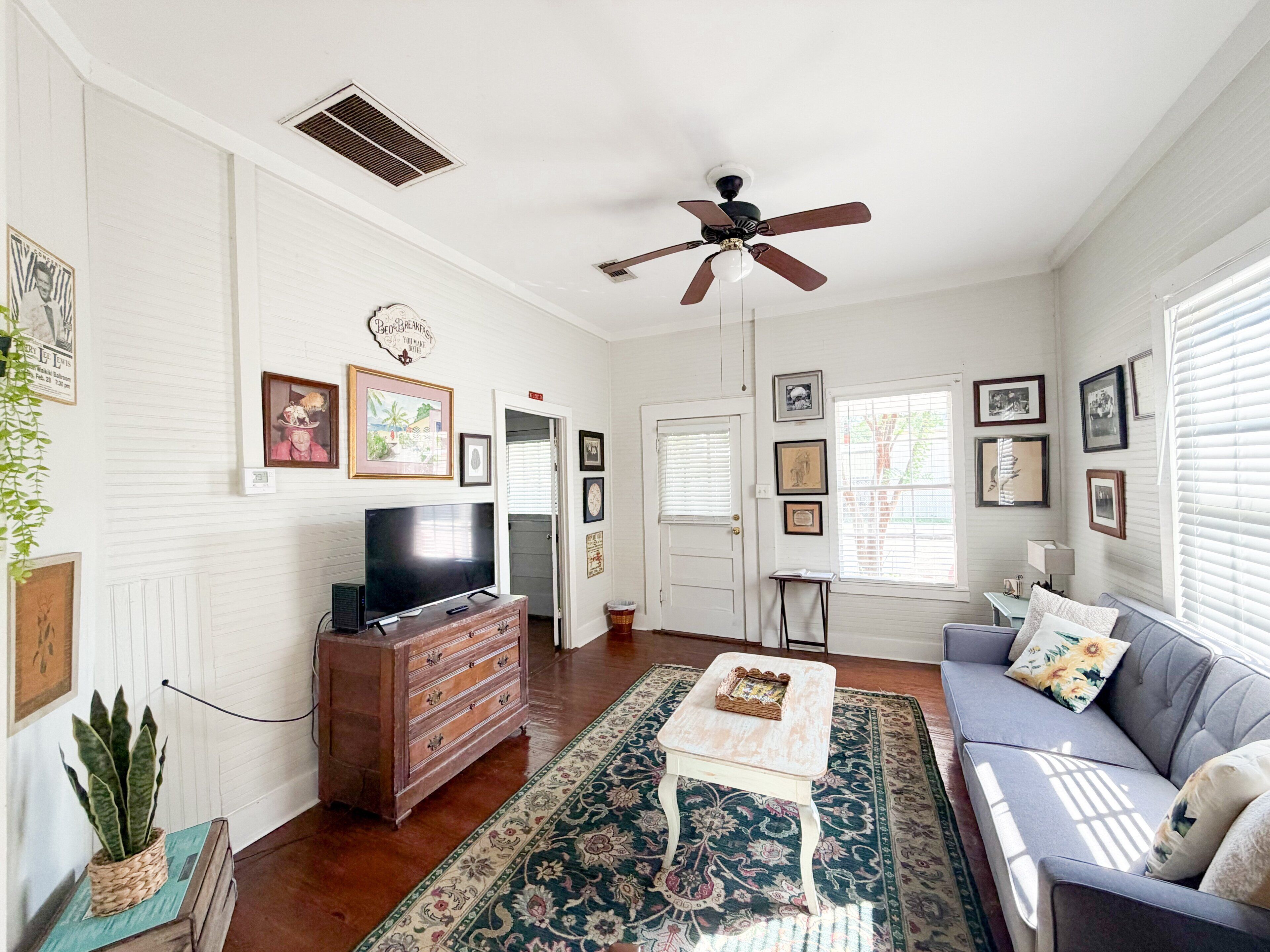 A living room with a television, a ceiling fan, a sofa, and a coffee table.