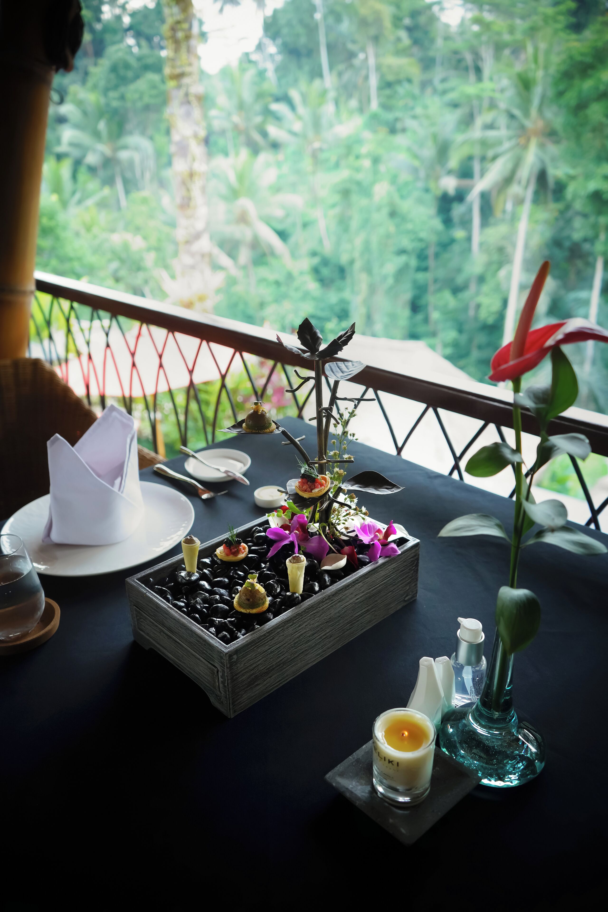 A dining table set with a candle, a small vase, and a decorative centerpiece.