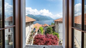 A view through a window of a building with a lake and mountains in the background.
