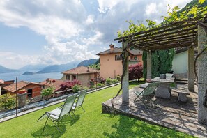 Una terraza con vistas al lago, mobiliario exterior y una pérgola.