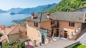 A hillside villa with a terrace, a view of the lake, and traditional architecture.