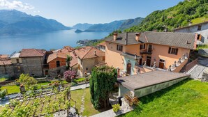 A hillside village with traditional architecture, a vineyard, and a lake view.